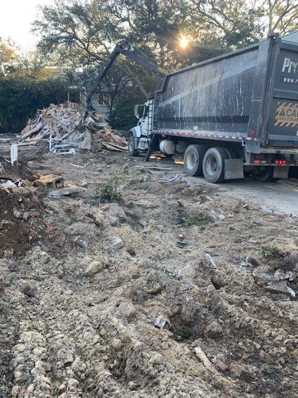 Cleared demolition lot with a debris pile and a loaded haul truck
