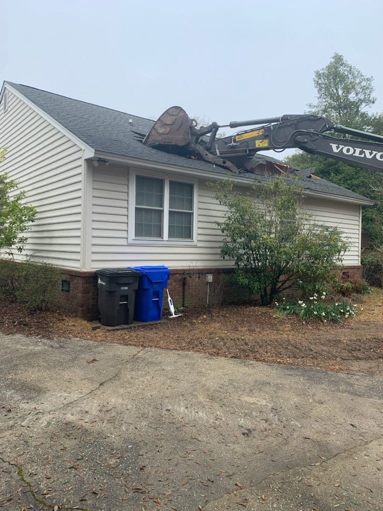 Volvo excavator pulling down the roof of a single-storey house